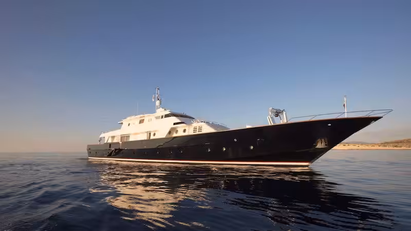 Luxurious black and white yacht sailing on calm ocean waters under a clear blue sky.