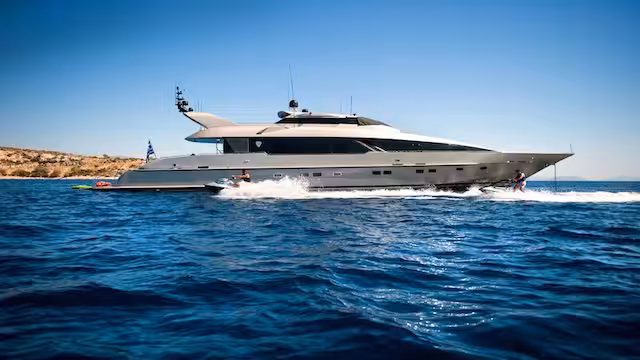 Luxury yacht cruising in clear blue waters under a sunny sky.