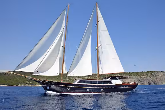 Luxury sailing yacht on open sea with white sails against clear blue sky, showcasing elegant design and marine travel allure.