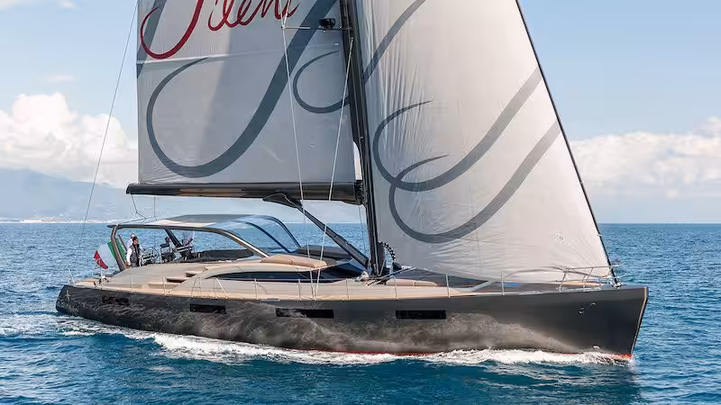 Luxury sailboat with sleek design cruising on open sea with clear skies and Italian flag displayed at the stern