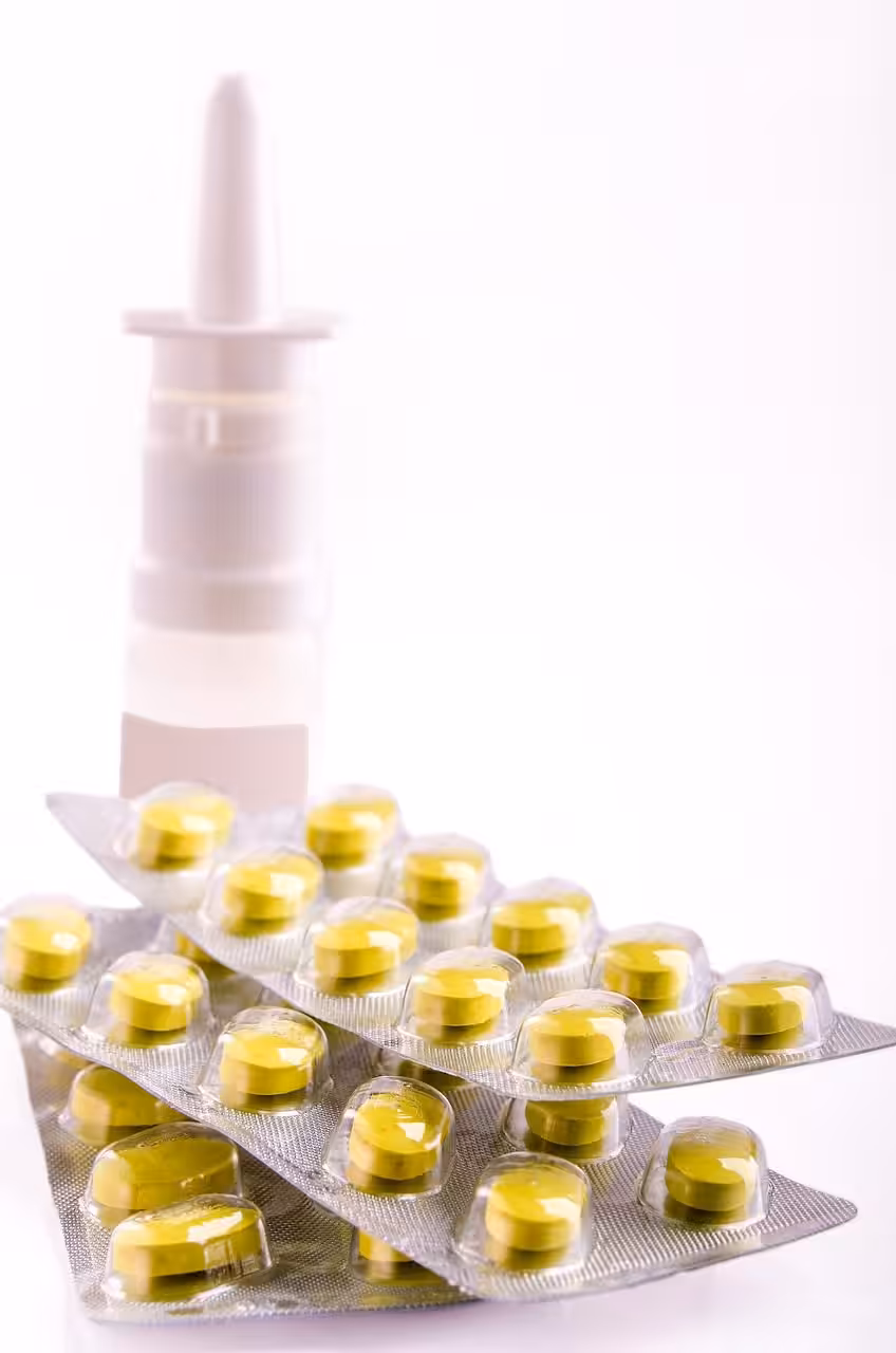Nasal spray and blister packs of yellow tablets on a white background.