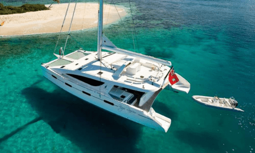 Luxury catamaran sailing near a tropical island with crystal clear water and sandy beach, ideal for vacation and adventure enthusiasts.