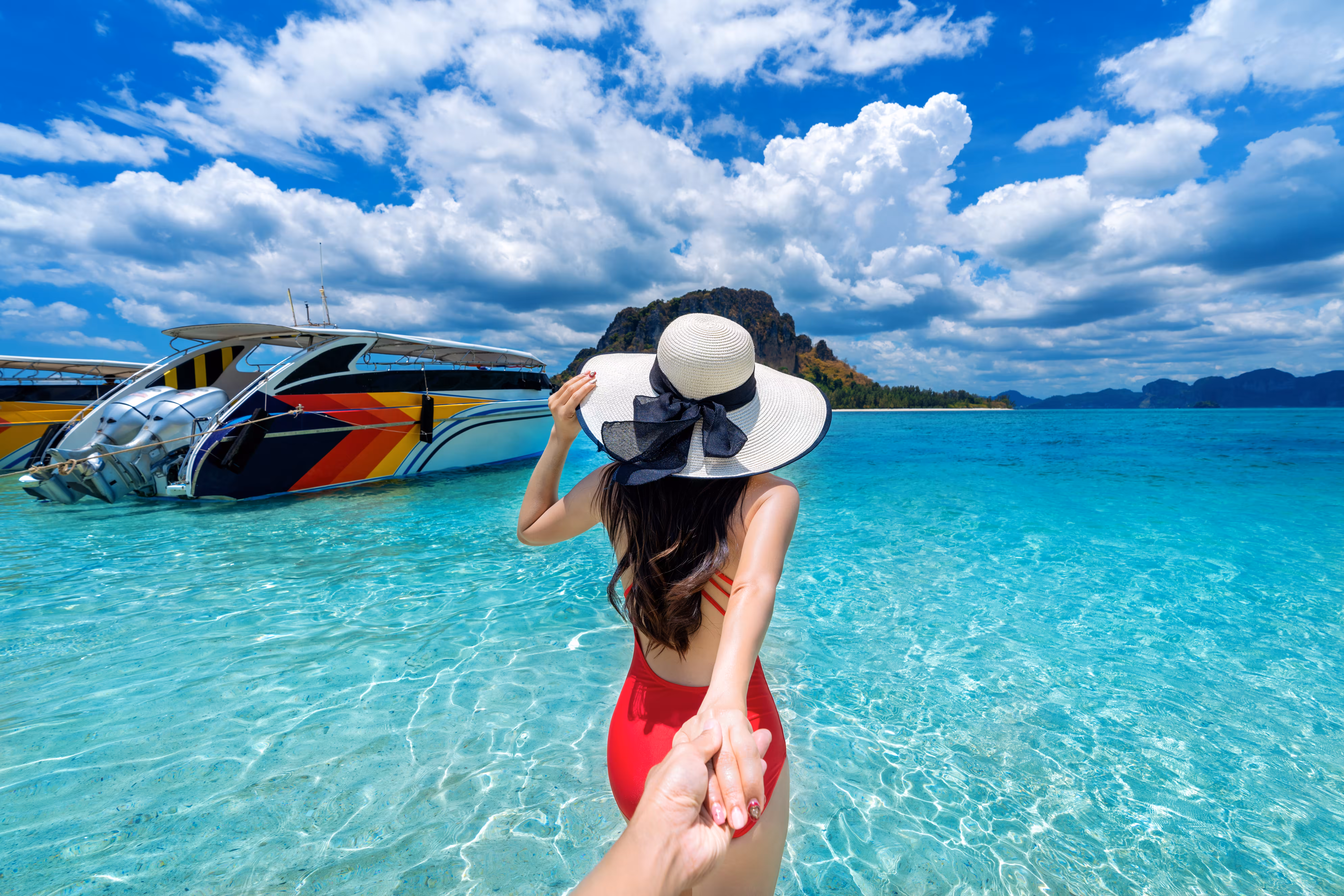 Bikini girl holding man's hand and leading him to ocean in Krabi, Thailand.