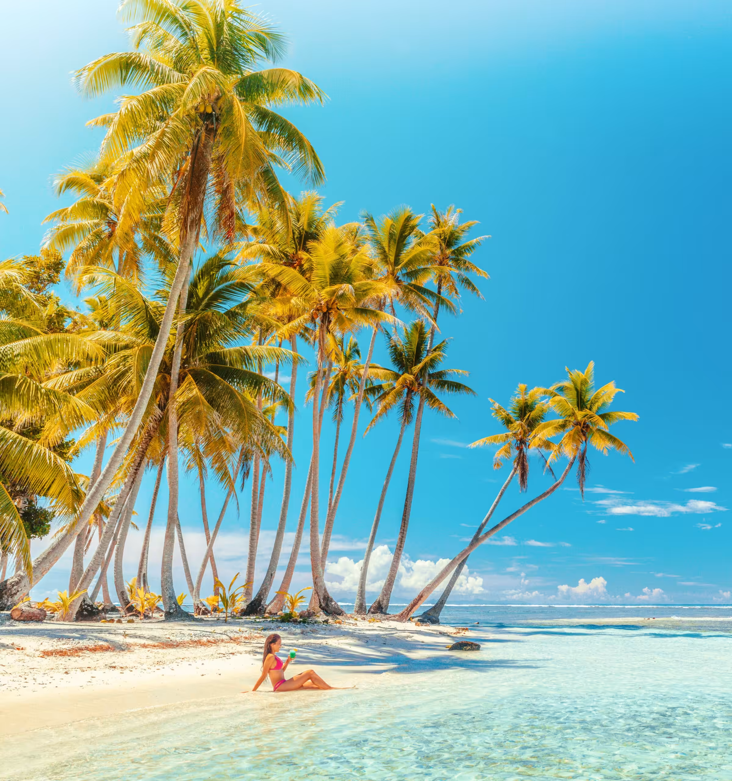 Travel vacation perfect iconic beach with beautiful woman in bikini on private beach island motu relaxing sipping on blue cocktail while sunbathing on French Polynesia travel. Cruise ship destination.